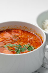 Bowl of curry with pieces of meat and a side of steamed rice arranged neatly for a meal