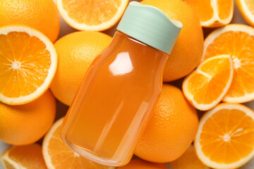 Composition with sports bottle of fresh orange juice and fruits as background