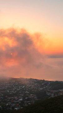 Volando sopra le nuvole all'alba con il sole giallo che spunta.
Ripresa aerea tra le nuvole, sole, mare e montagna. San Felice Circeo, Lazio, Italia.  Video verticale.