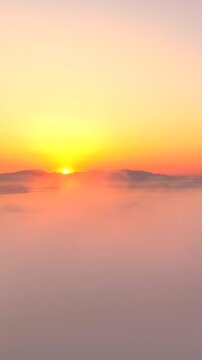Volando sopra le nuvole all'alba con il sole giallo che spunta.
Ripresa aerea tra le nuvole, sole, mare e montagna. San Felice Circeo, Lazio, Italia.  Video verticale.