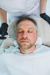 Obraz premium Male cosmetology. A man lies at a cosmetologist for a facial treatment.