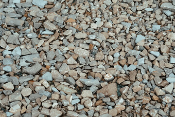 A close-up view of various sizes of gravel stones scattered on a surface in natural sunlight during...