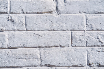 Textures of a whitewashed brick wall in bright sunlight highlighting surface details and shadows