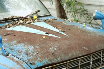Abandoned blue old car, rust and paint faded on hood