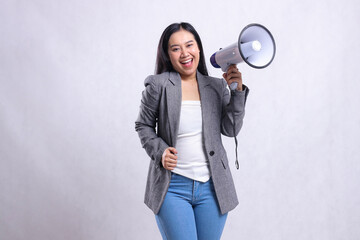 beautiful formal young girl shouting happily to the camera hand holding megaphone loudspeaker and holding wearing gray suit isolated on white background. fashion concept, lifestyle, advertising