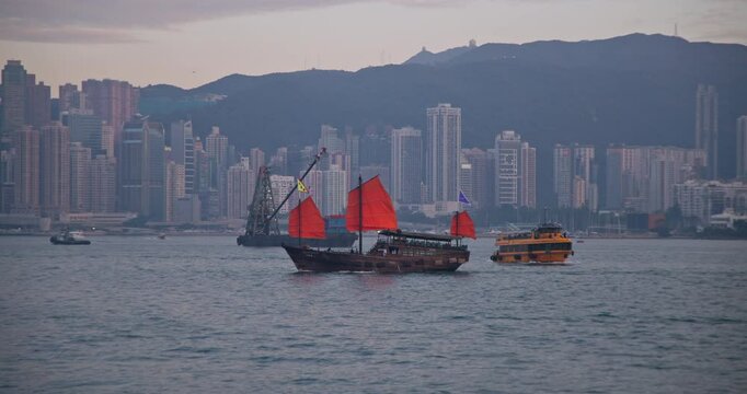 Hong Kong Victorial Harbour Cityscape with Traditonal Red Sailing Junk Boat and Dense Buildings