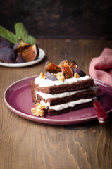 Piece of chocolate cake with nuts, violet figs and whipped cream on violet-pink plate. On vintage background for autumn concept. 