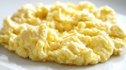 Fluffy scrambled eggs with a smooth texture, sitting on a white surface, offering a fresh and simple breakfast presentation.