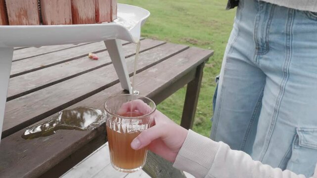Close-up of a glass being filled with freshly squeezed apple juice from a machin