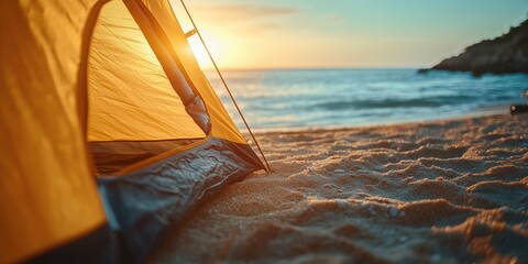 Scenic coastal camping with a beach sunset view. Yellow tent pitched on the sandy beach beside the tranquil ocean.
