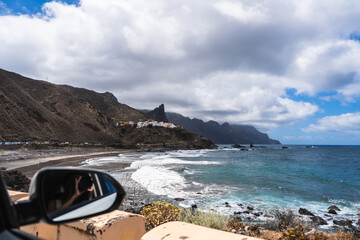 Car window coastal drive along the rocky shoreline with waves crashing the beach