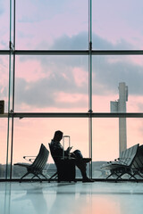 Businessman is using his smartphone while sitting in an airport terminal waiting for his flight