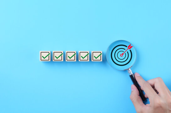 Business Strategy Planning and Quality Management Concept. Magnifying glass focuses on target icon and blocks with check marks. business goal setting, strategy planning, quality management processes,