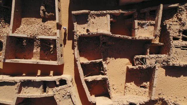 Person walking between ancient ruins of Chinguetti, desert of Mauritania. Aerial top-down view