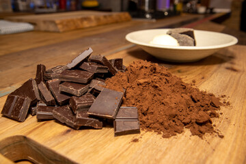 Chocolate pieces and coco powder on a wooden background, cooking ingredient concept