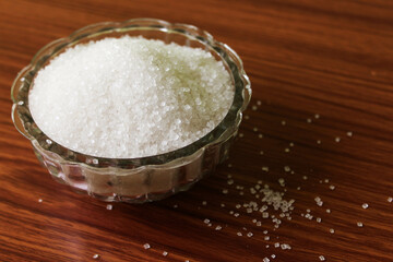 White sugar in bowl on wood background. selective focus with blur
