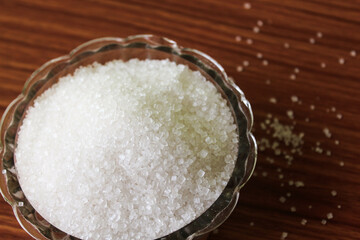 White sugar in bowl on wood background. selective focus with blur
