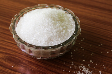 White sugar in bowl on wood background. selective focus with blur

