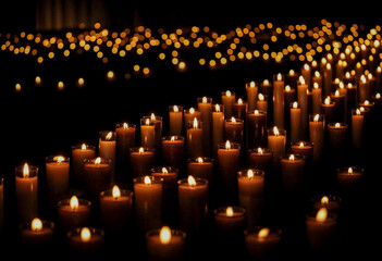 Centinaia di candele accese in una chiesa, disposte in file ordinate, illuminano l’ambiente in un’atmosfera suggestiva e contemplativa