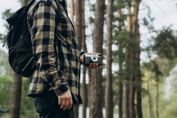 Male photographer with a film camera in a pine forest, analog photography.