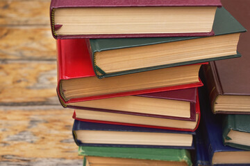 Pile of old hardcover books on wooden rustic background. Close up photograph. 