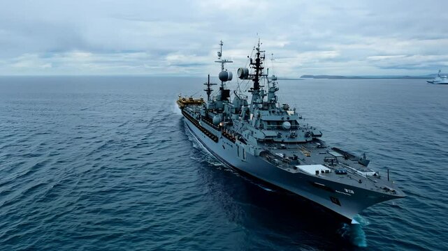 Military naval ship cruising on open sea under cloudy sky