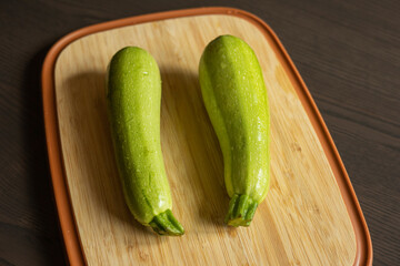 Two Fresh Zucchini on a Cutting Board Close-Up on Dark Background