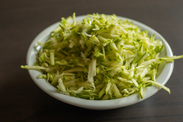  Shredded Zucchini in a White Bowl Close-Up on Dark Background