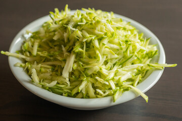  Shredded Zucchini in a White Bowl Close-Up on Dark Background
