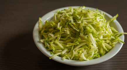 Shredded Zucchini in a White Bowl Close-Up on Dark Background