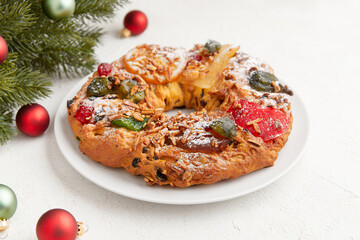 A festive cake adorned with candied fruit and nuts, surrounded by holiday decorations and ornaments