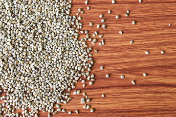Organic Pearl Millet (Pennisetum glaucum) or Bajra, in a bowl. Isolated on a brown wooden...