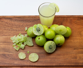 A glass of Amla juice ,chopped amla and whole amla also known as Indian gooseberry placed on a...