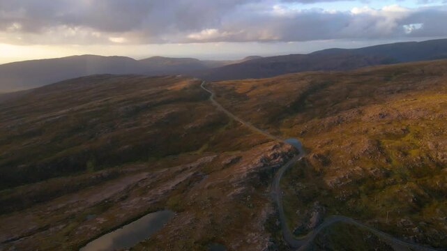 Drone shot flying over the Applecross pass road over the Bealach na B&agrave; pass in the Scottish highlands at sunset.