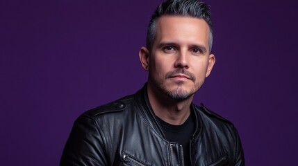 Obraz premium A man in a black leather jacket is standing in front of a purple background