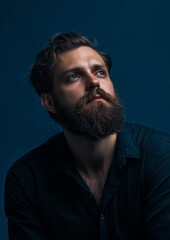 Obraz premium A man with a beard and a blue shirt is looking up
