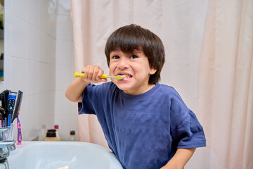 child brushing his teeth while looking at the camera