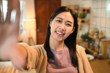 Cheerful young woman taking selfie in her home kitchen. Camera point of view