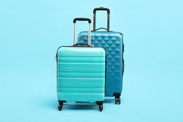 Different bright suitcases on light blue background