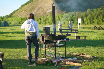 Young woman cooking outdoors on barbecue in Siberia