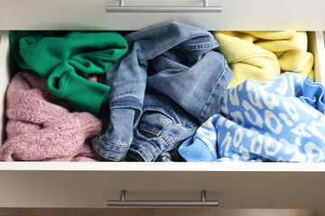Cluttered chest of drawers indoors, closeup. Clothes in mess