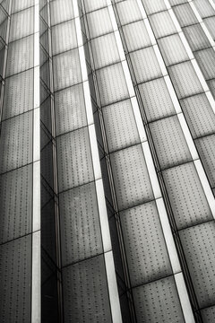 Tall skyscraper wall with an abstract monochromatic pattern of repetitive vertical lines and dotted textures creating a sense of modernity and simplicity.