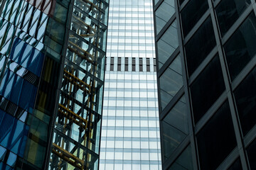 Three skyscrapers with contrasting architectural styles and materials, including glass and steel, highlighting the diversity of design in a dense urban environment.