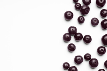 Ripe acai berries on white background, flat lay. Space for text