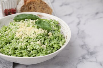 Tasty spinach risotto served on white marble table, closeup. Space for text