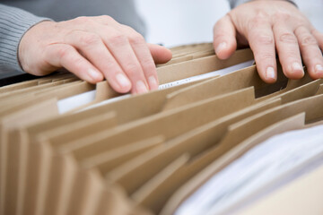Close up of a man hands flicking through a file folder
