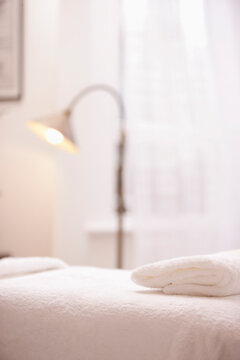 Close up of a folded white towel on a massage table
