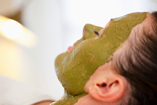 Profile of a woman with green facial mask
