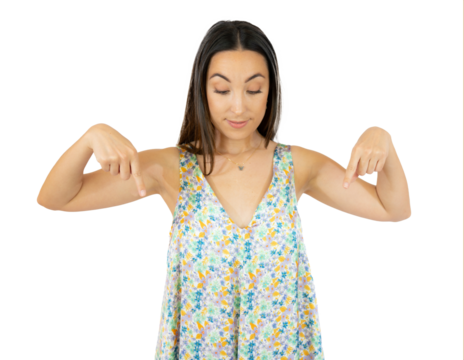 Young natural caucasian woman points down with fingers, positive feeling over transparent background.