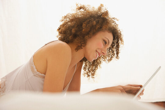 Woman Lying on Bed Using Digital Tablet
